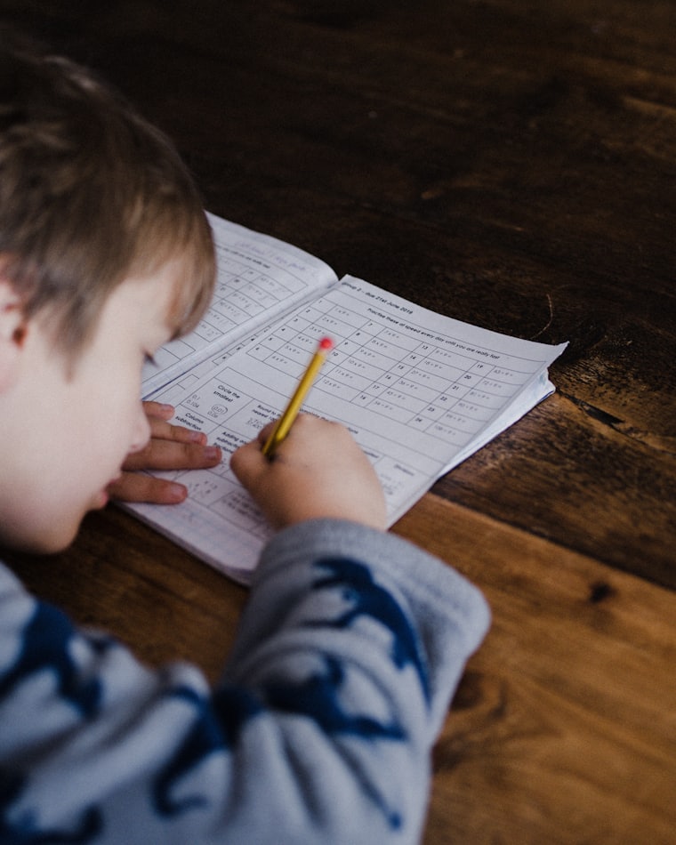 A young boy struggling to concentrate over a school exercise book
