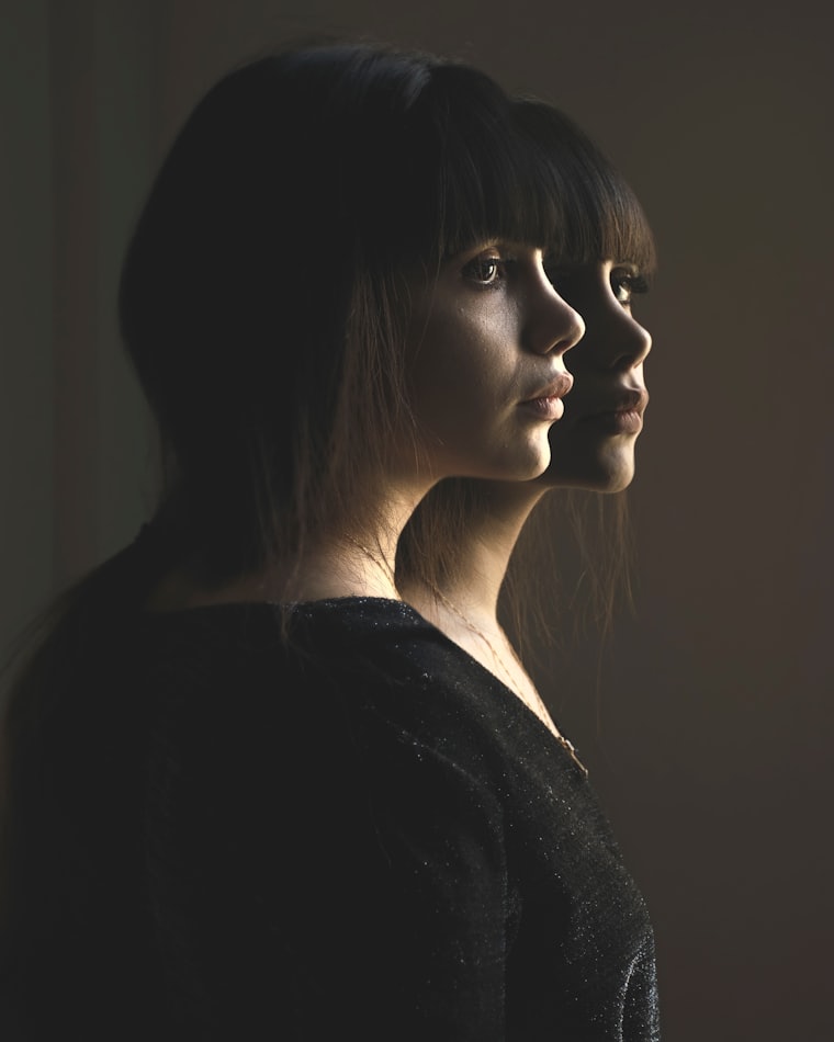 A double-exposure portrait showing the same face twice, in light and in shadow