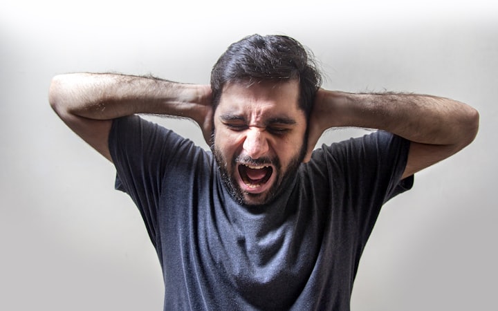 A man in acute distress, hands clamped over his ears